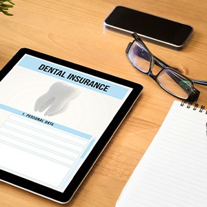 Dental insurance form on tablet next to notepad