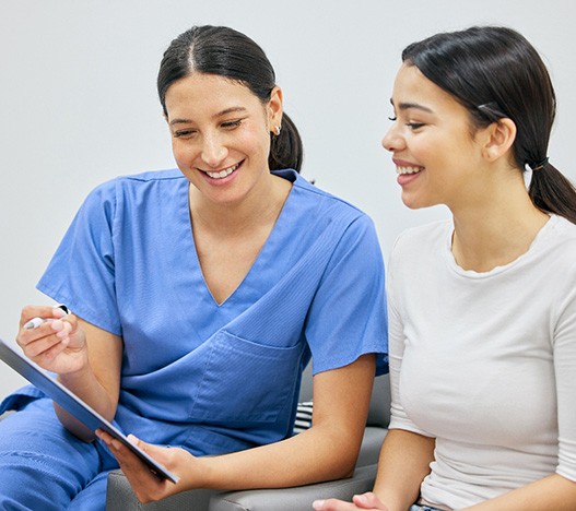 Dental assistant showing patient forms on clipboard