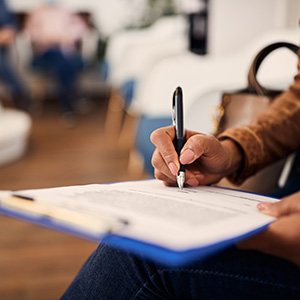 Patient filling out forms on clipboard in lobby