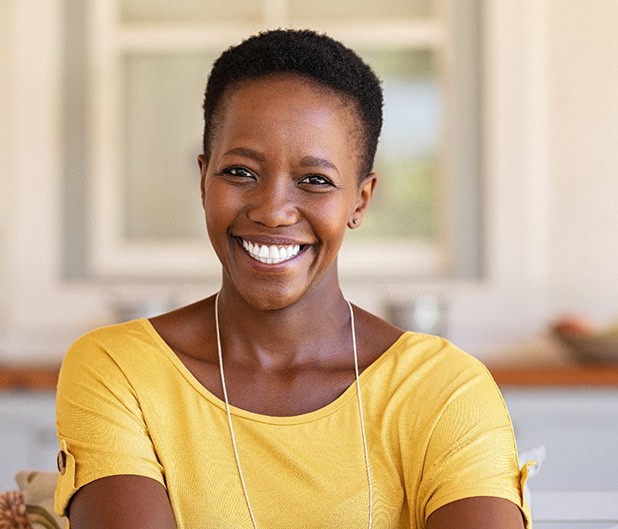 Woman in yellow shirt smiling at home